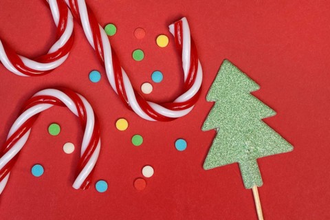 Candy canes and sugar confetti against red background, Christmas
