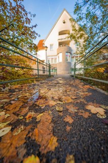 Autumn bridge with fallen leaves leading to a house, Aidlingen, Böblingen district, Germany