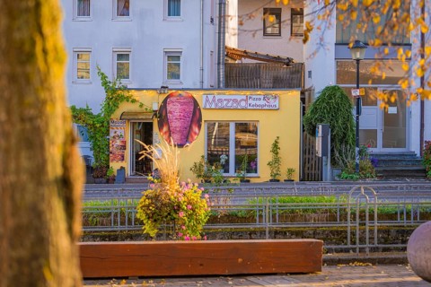 Yellow pizza building on a sunny street surrounded by autumn plants, Aidlingen, Böblingen district,