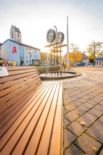 Municipal square with church and sculpture at sunset, concrete paving and autumn trees, Aidlingen,