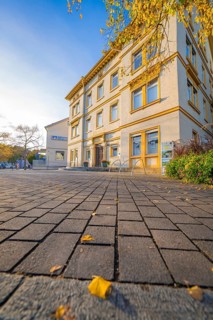 Two-story building with autumn leaves on the forecourt, under blue sky, Aidlingen, Böblingen