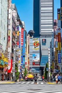 Bustling street scene in Japan with modern buildings and colorful billboards, figure of Godzilla