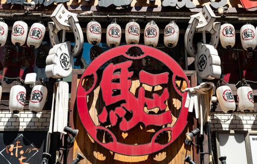 Red sign with Japanese characters, bar entrance decorated with lanterns, Shinjuku City, Tokyo,