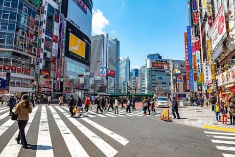 Large intersection with billboards and colorful signs at shops and restaurants, busy downtown with