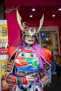 Futuristically dressed mannequin with colorful armor, cosplay, in front of a restaurant, Shinjuku
