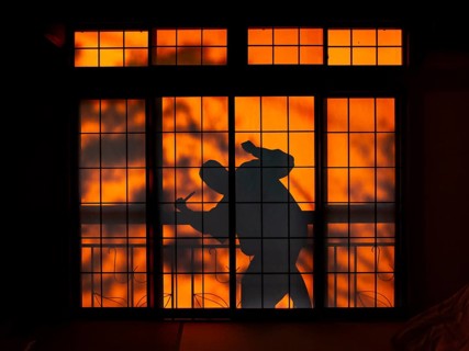 Shadow of a man, burglar with knife, assassin, ninja, on the balcony behind sliding shoji doors in