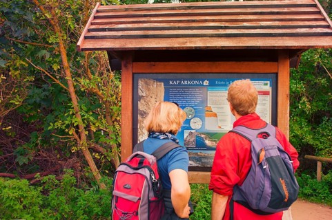 Tourist couple in front of information board of Cape Arkona, coast of Rügen, largest German island,