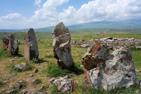 Set of stones in a vast landscape with mountains and clouds in the background, stone circle,