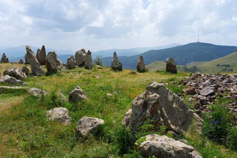 Stone formations in a meadow with a view of cloudy mountains, stone circle, megaliths, Zorats