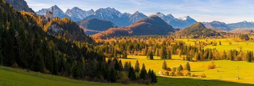 Panoramic picture, landscape with green fields, Neuschwanstein Castle and mountains in the