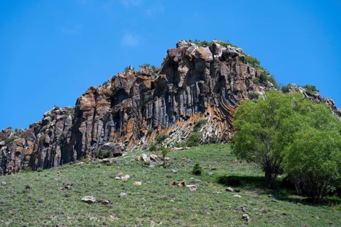 Mighty rock formation with lush greenery and clear skies, radiating peace and natural beauty,