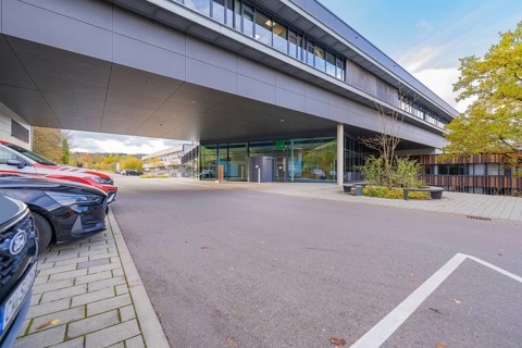 Parking lot in front of a modern, grey office building under clear skies, Calw District Office,
