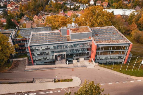 Modern office building with solar panel on the roof and surrounding autumn trees, Calw District