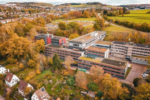 Multi-storey building complex with colorful autumn trees in rural surroundings, Calw District