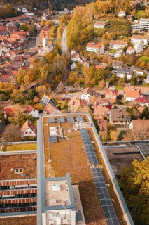 Building with a flat roof and solar cells next to an idyllic, autumnal urban landscape, Calw