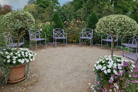 Quiet garden with purple chairs, surrounded by trees and flowering plants, Kreislehrgarten