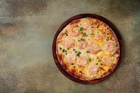 Four cheese pizza with shrimp and fresh microgreens, served on a wooden board, homemade, no people