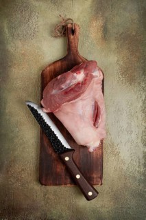 Raw pork knuckle, on a wooden chopping board, close-up, top view, no people