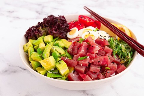 Fresh poke bowl, with tuna, avocado, and vegetables, served on a white plate
