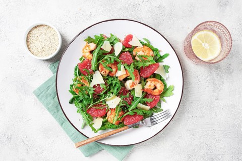 Fresh shrimp salad with arugula, grapefruit, and parmesan served in a bowl