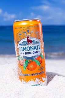Adjara mandarin lemonade, Borjomi, aluminum can, on the beach sand, against the background of the