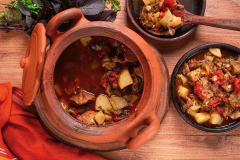 Chanakhi, a Georgian dish. in a clay pot, on a wooden table, stewed meat with vegetables, homemade,