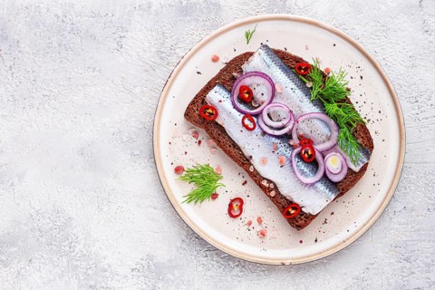 Sandwiches, Herring fish, on dark rye bread, sprinkled with onion, chili pepper and herbs, on a