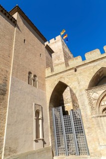 Looking up at historic tower and ramparts in courtyard of historic castle, Aljafería Palace,