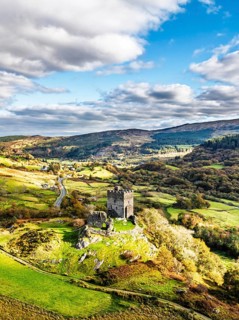 DefAutumn colours over Castell Dolwyddelan and Eryri Mountains from a drone, Snowdonia, Conwy