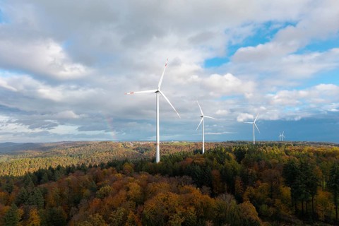 Three wind turbines above a colorful autumn forest under a cloudy sky, near Schorndorf, Remstal,