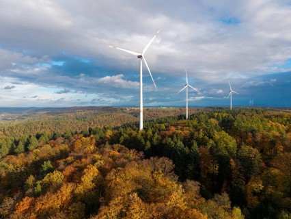 A wind farm rises above an autumnal forest under a cloudy sky, near Schorndorf, Remstal,