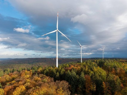 Three wind turbines above an autumnal forest against a cloudy sky, near Schorndorf, Remstal,