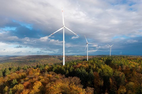 Wind turbines stand in a colorful autumn forest under a changing sky, near Schorndorf, Remstal,