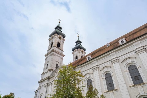 Baroque church with two towers and richly decorated exterior façade under cloudy sky, ZFP