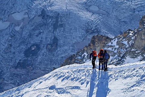 Three ascended mountaineers run across a snow-covered mountain ridge, Aiguille du Midi,