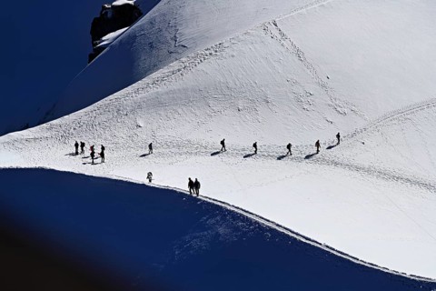 A group of mountaineers runs across a snow-covered mountain, Aiguille du Midi, Chamonix-Mont-Blanc,