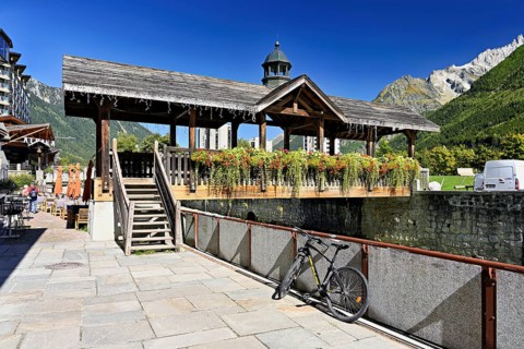 Old wooden bridge decorated with flowers that crosses the glacial river Arve, Chamonix-Mont-Blanc,