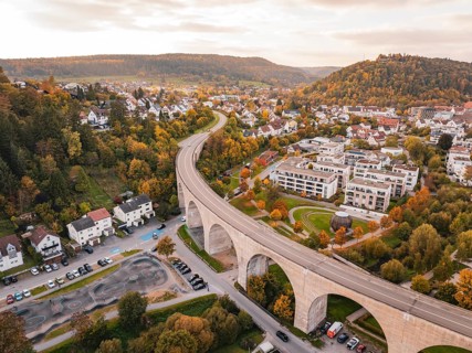 Curvy bridge over an urban road surrounded by colorful autumn trees and houses, Nagold, Black