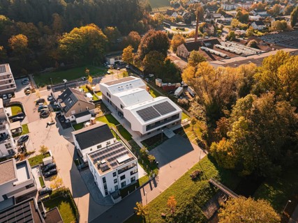 Picturesque overview of a small settlement with solar panels on the roofs in autumn surroundings,