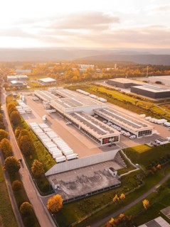 Extensive industrial park with parked trucks and buildings, in colorful late afternoon light,