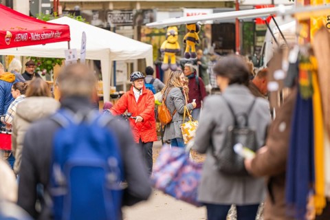 Lively market with people wearing winter clothes, surrounded by various stalls and decorations,