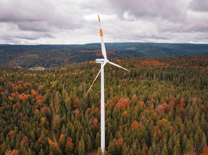 Wind turbine high above a colorful autumn forest on a hill, Simmersfeld wind farm, Germany