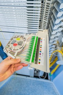 Hand holding a fiber optic cabling module in a technical environment, optical fiber