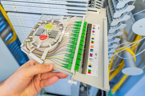Close-up of a hand holding a fiber optic cabling module, optical fiber
