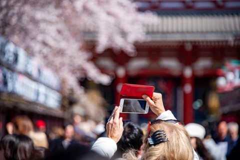 Tourist taking pictures with her cell phone, numerous visitors on Nakamise-dori shopping street,