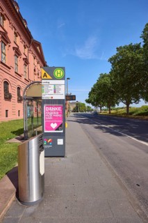 Landtag bus stop, New Armoury, historic building, public trash can, lantern, trees, lawn, blue sky,