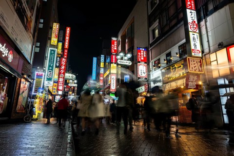 Busy pedestrian zone with many shopping centers and stores, illuminated with lots of neon signs at