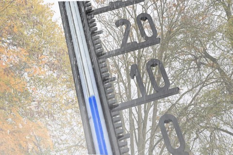 (photo montage) Thermometer in front of autumn-colored deciduous tree shows cool temperatures