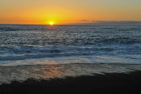 Idyllic sunset on calm calm seas of the eastern Atlantic Atlantic with gentle waves on lava beach,