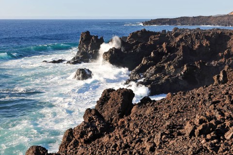 Strong surf claps blazes with white spray white foam from moving sea during swell on rocky coast of
